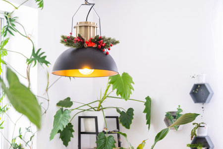 Black retro metal loft style lampshade with Christmas decor and many indoor plants on a window in a white interior. New Year, comfort at homeの写真素材