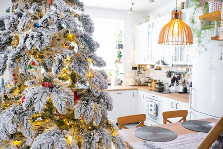Festive Christmas decor in white kitchen, modern rustic interior with a snowy Christmas tree and fairy lights. New Year, Christmas mood, cozy home. The general planの写真素材