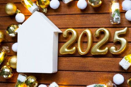 House key with tiny figure of home mock up on festive brown wooden background, lights of garlands. New Year 2025 wooden letters, greeting card. Purchase, construction, relocation, mortgage, insuranceの写真素材