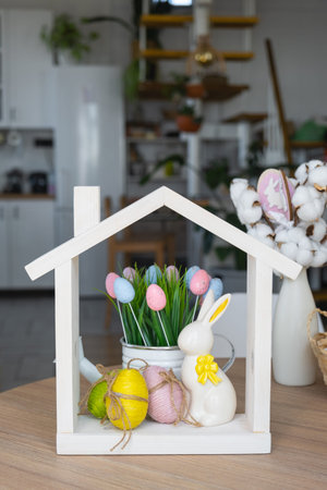 Tiny house of cozy home with Easter decor with rabbit and eggs on table of kitchen. Building,...