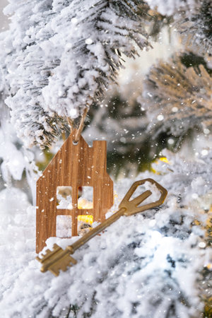 Key and tiny house keychain in hand on background fairy lights Christmas tree. gift for New Year, Christmas. Building, design, project, moving, insurance, mortgage, rent and purchase real estate.の写真素材