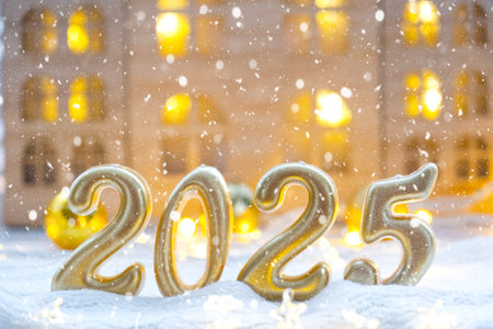 Golden figures number 2025 against the background of cozy windows of a house with warm light with festive decor of stars, snow and garlands. Greeting card, Happy New Year, cozy homeの写真素材