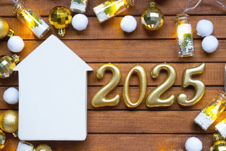 Golden figures number 2025 and tiny home on background of cozy windows of a house with warm light with festive decor of stars, snow and garlands. Greeting card, Happy New Year, cozy homeの写真素材