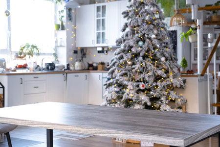 Gray Wooden empty table to demonstrate product with space for text with upholstered chairs in white kitchen, modern interior with Christmas tree and fairy lights. New Year, Christmas mood, cozy home.の写真素材
