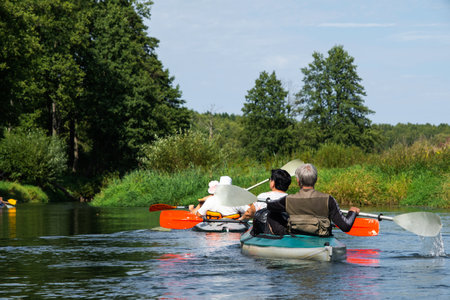 Group kayak trip for an elderly couple. Adult rowing boat on the river, a water hike, a summer adventure. Age-related sports, mental youth and health, tourism, active old ageの写真素材