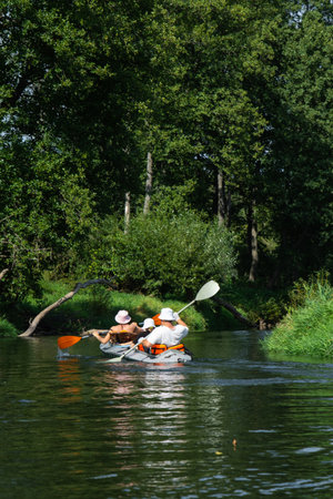 Family with children on rafting trip in Group kayak trip of different ages, adults, elderly. Rowing boat on the river, a water hike, summer adventure.の写真素材