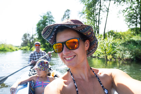 Man and woman couple, child 8 years old, selfies are happy in family kayak trip rowing boat on the river, water hike, a summer adventure. Eco-friendly tourism, active and healthy lifestyleの写真素材