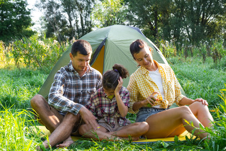 Family uses a repellent outdoor camping and picnicking near a tentの写真素材