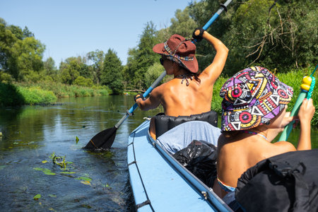 Family kayak trip. Mom and daughter rowing a boat on the river, a water hike, a summer adventure. Eco-friendly tourism, active and healthy lifestyleの写真素材