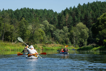 Family with children on rafting trip in Group kayak trip of different ages, adults, elderly. Rowing...