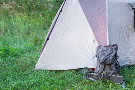 Installed tourist tent And backpack in a camping in nature in the forest. Domestic tourism, active summer holidays, family adventures. Ecotourism, sport, hike. Copy space, mock upの写真素材