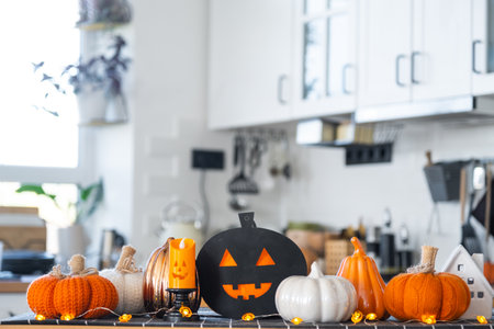 Decor of white classic kitchen with pumpkins, garlands, jack latern for Halloween and harvest with figurine of house. Autumn mood in home interior, modern loft style.の写真素材
