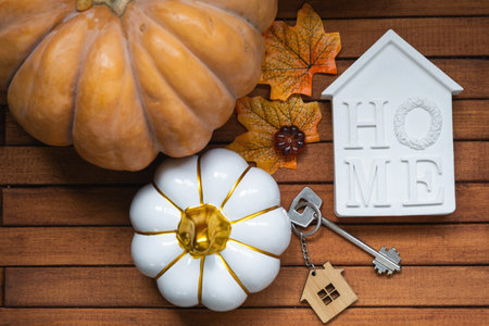 Cozy layout on a wooden background of slats with pumpkins, autumn leaves, a tiny house and keys - autumn mood, Halloween, housing, relocation.の写真素材