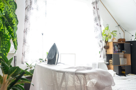 The iron is on the ironing board with a plain cloth in the room in close-up.の写真素材