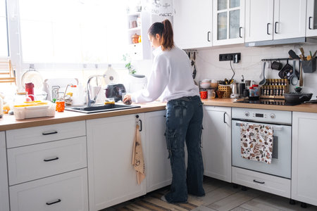 A woman cooks and cleans in the kitchenの写真素材