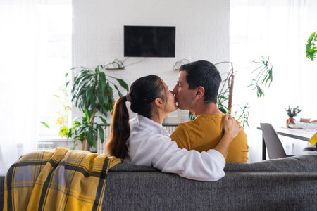 Man and woman at home in a white interior sits on the couch and watches TV. Home recreation, leisure, love, family, dateの写真素材