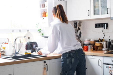 A woman cooks and cleans in the kitchenの写真素材