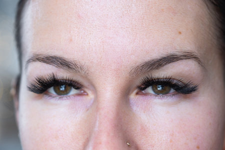 A woman has long extended eyelashes in a close-up with rhinestones.の写真素材