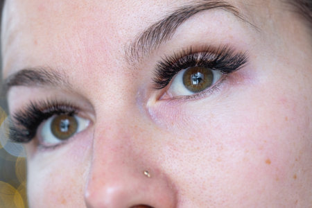 A woman has long extended eyelashes in a close-up with rhinestones.