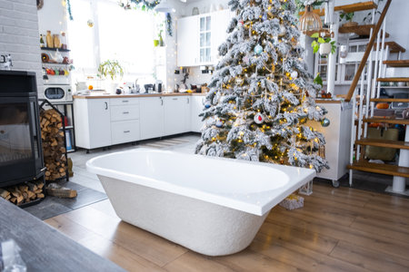 New bathtub under festive Christmas tree as New Year's gift in interior of white modern decorated kitchen. Interior renovation and design, construction and home improvementの写真素材