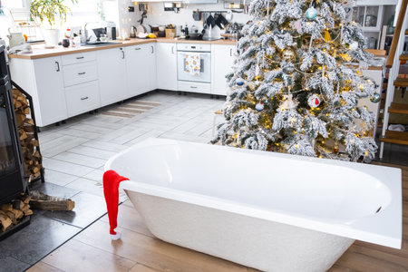 New bathtub under festive Christmas tree as New Year's gift in interior of white modern decorated kitchen. Interior renovation and design, construction and home improvementの写真素材