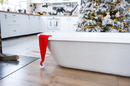 New bathtub under festive Christmas tree as New Year's gift in interior of white modern decorated kitchen. Interior renovation and design, construction and home improvementの写真素材