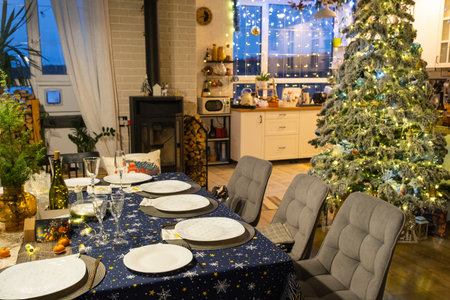 Festive interior of house is decorated for Christmas and New Year in loft style with black stove, fireplace, Christmas tree. Warm studio room with set table, burning wood, cozy and heating of homeの写真素材