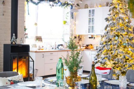 Festive interior of house is decorated for Christmas and New Year in loft style with black stove, fireplace, Christmas tree. Warm studio room with set table, burning wood, cozy and heating of homeの写真素材