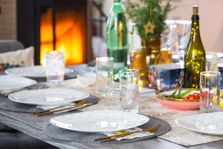 A festive table set for guests for Christmas and New Year, a Christmas tree in the living room, plates, bottles, glasses, potted plants, fairy lightsの写真素材