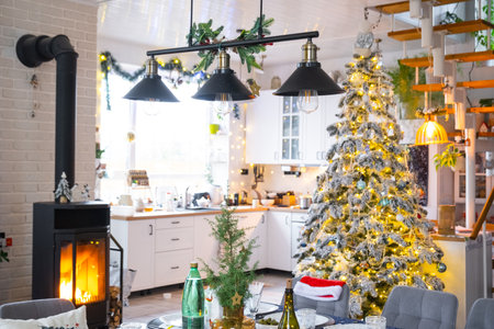 Festive interior of house is decorated for Christmas and New Year in loft style with black stove, fireplace, Christmas tree. Warm studio room with set table, burning wood, cozy and heating of homeの写真素材