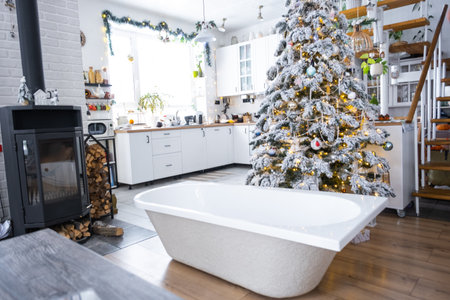 New bathtub under festive Christmas tree as New Year's gift in interior of white modern decorated kitchen. Interior renovation and design, construction and home improvementの写真素材