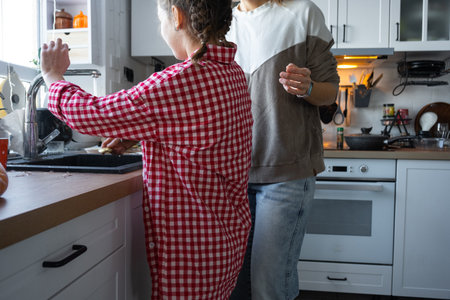 The girl cooks her own breakfast in the kitchen, washes the dishesの写真素材