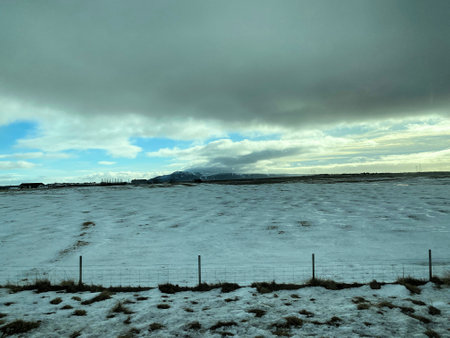 Icelandic winter landscape with snow covered hills and blue cloudy skyの写真素材
