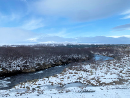 Icelandic winter landscape with snow covered hills and blue cloudy skyの写真素材