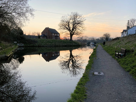 A view of a narrow boat crossing a canal in the countryside.