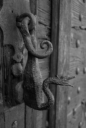 Original metal knocker on an old wooden door in black and white