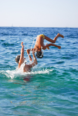 Dad and son is playing into the blue seaの写真素材