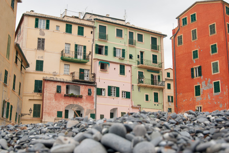 Grey stones on the beach of Camogli and typical colorful housesの写真素材