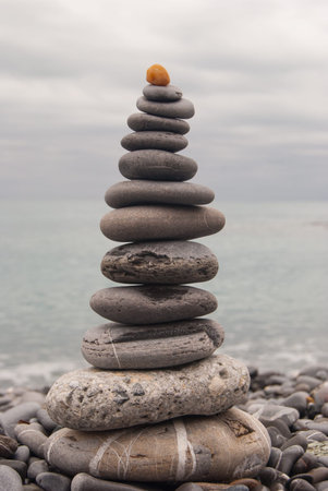 Pyramid of stones on the beach and leaden sky