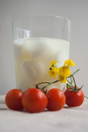 Glass with mozzarelle milk fresh tomatoes and yellow flowersの写真素材