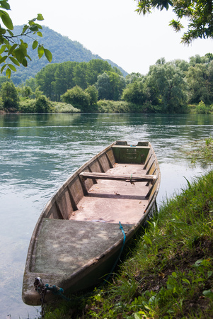 Long and particular rowing boat tied at the bank of the riverの写真素材