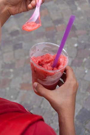 Granita to take away in a plastic cup with pink spoon and lilac drinking strawの写真素材