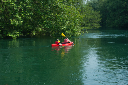 Woman and man are paddling on a red kayak on Adda riverの写真素材