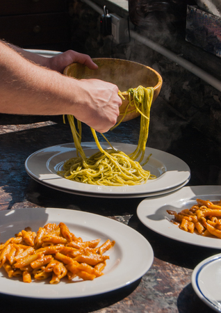 Waiter serving pasta with pesto and penne with red sauceの写真素材