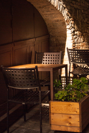 Two chairs and a table with geranium on it outside an Italian restaurantの写真素材