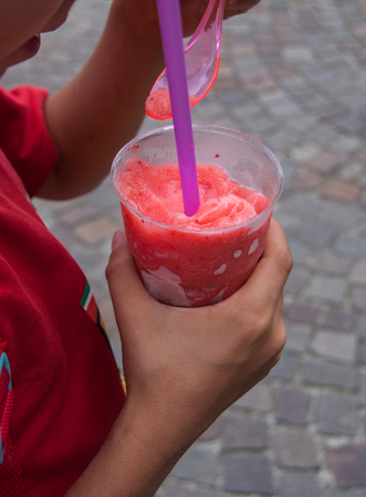 Granita to take away in a plastic cup with pink spoon and lilac drinking strawの写真素材