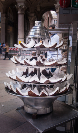 Pieces of coconut with fresh water exposed in a kiosk for selling in Milanの写真素材