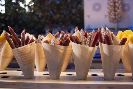 Cone-shaped wooden containers with salami and some with local pieces of cheeseの写真素材