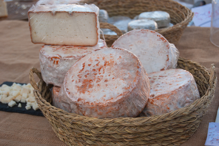 Wicker basket with cheese and little pieces for tasting it at the local weekly marketの写真素材