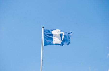 Blue fluttering banner with a glass of white beer on itの写真素材